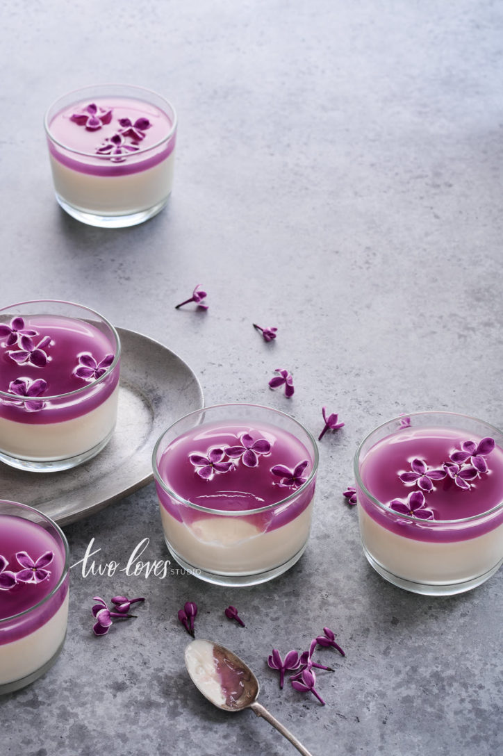 White chocolate pana cotta dessert with lilac flowers on a marble background. 