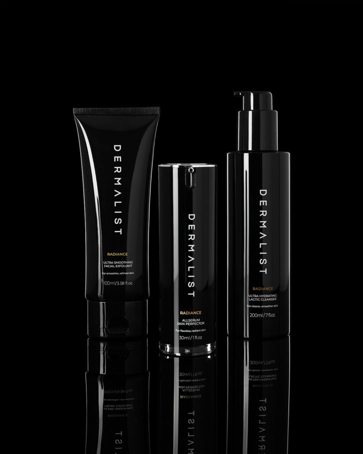 Three black bottled skin care products in from of a black background. This shot was taken using the low key product photography set up.