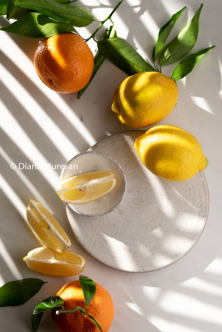 Lemons and oranges and their green leaves on a white background.