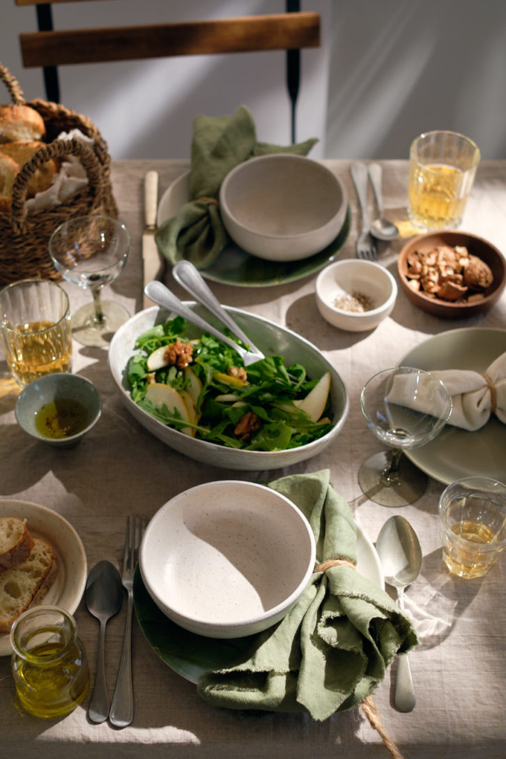 Dinning table set with a variety of dishes and glasses on a cotton table cloth. 