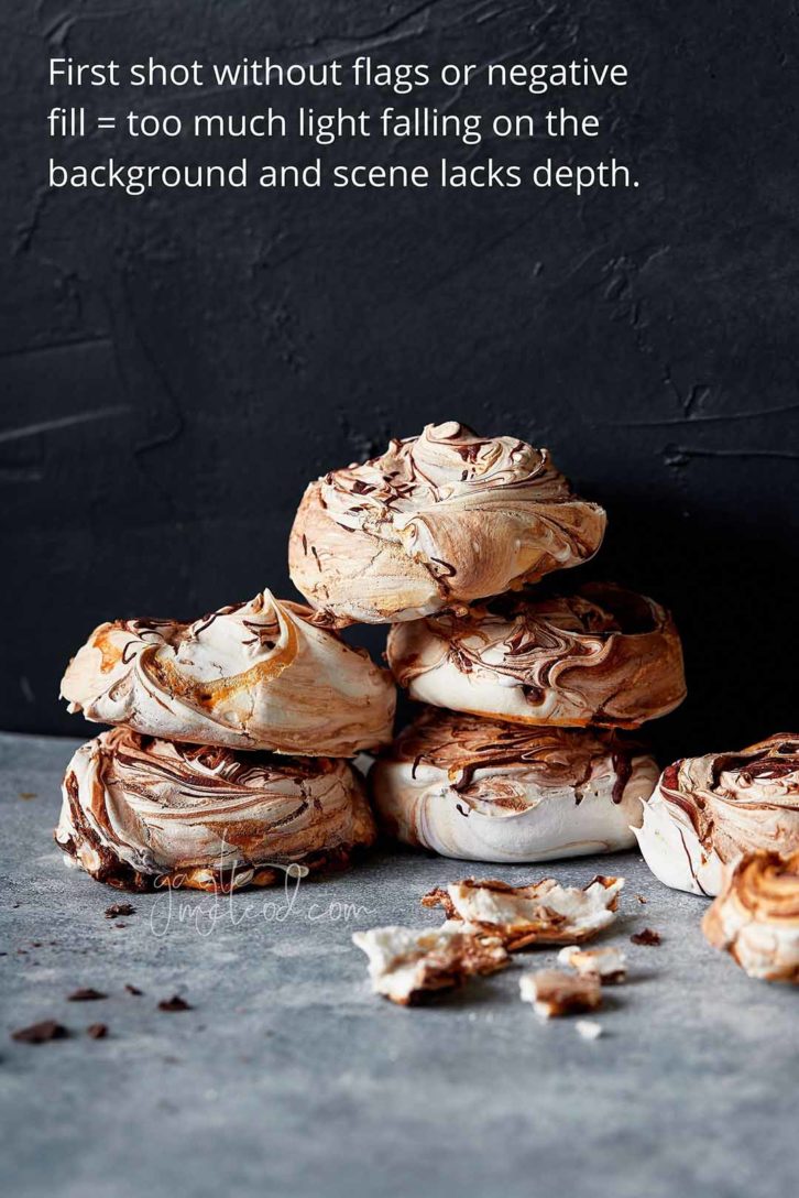 A black background with 6 meringues stacked in a pile on marble. Showing where to place the first flag to the front left of the shot. 