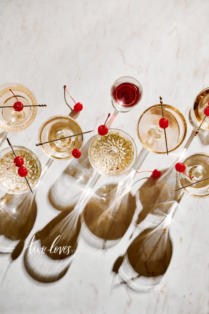A marble background with a number of different cocktail glasses and cherry garnishes. 