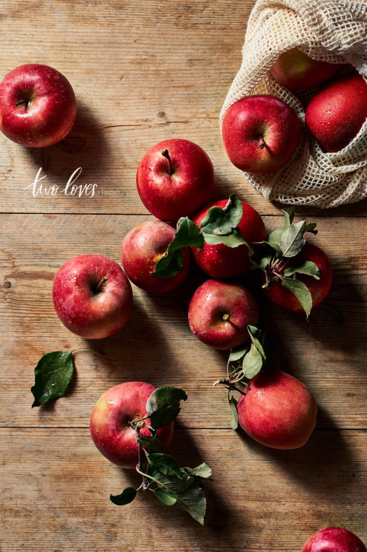 Rachel Korineks current Food Photography Style. Wooden backdrop with a bag of red apples spilling out. 