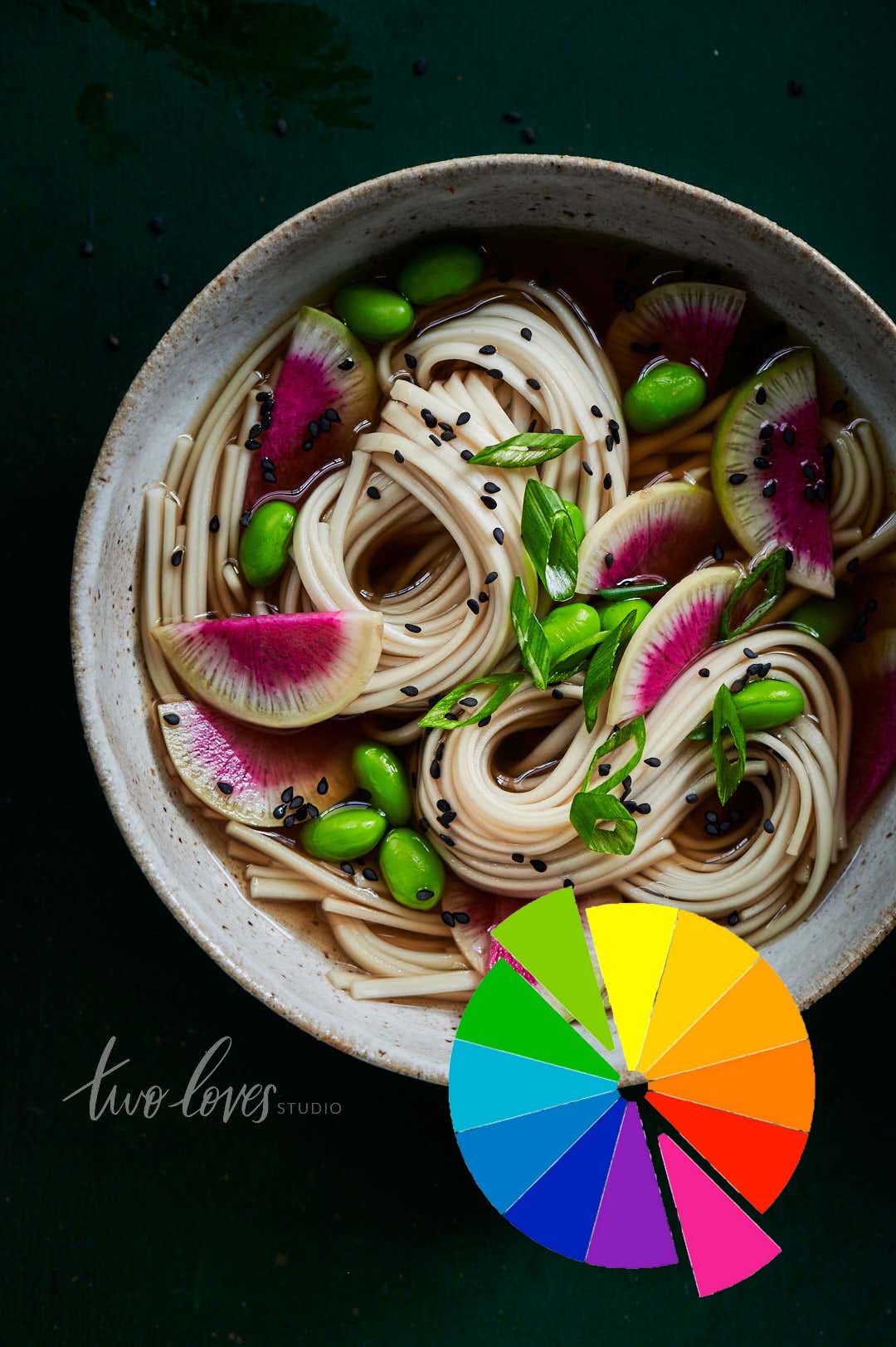 Black background with a clay bowl filled with noodle soup and black sesames on-top. 