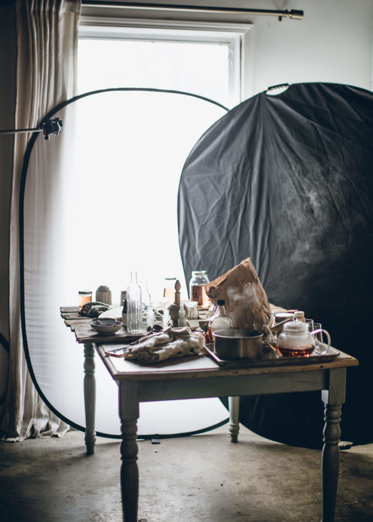 Wooden table showing natural lighting set up with a partially covered window using a black diffuser on the right-hand side.