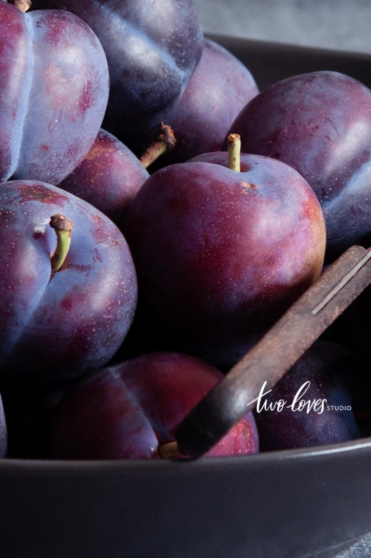 200mm focal length shot of plums in a black bowl. 