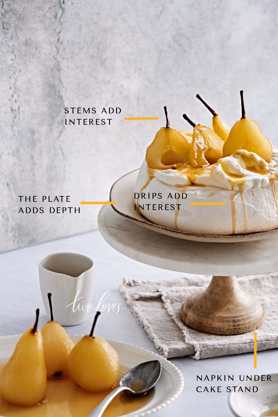 Soft marble backdrop. A meringue ontop of a cakestand. Pear fruit balanced on top. 