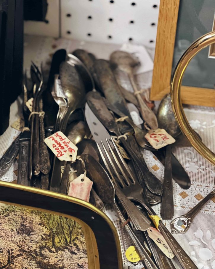 A bundle of vintage cutlery from a thrift store on a white table cloth. 