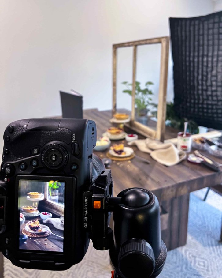 A dinning room table with the faux window, a light box behind it. An assortment of plates and items on the table. 