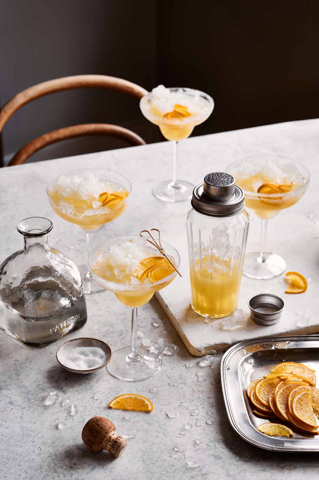4 orange margarita glasses on a table with garnishes. Showing someone how a final edit would look when editing cocktail photos.