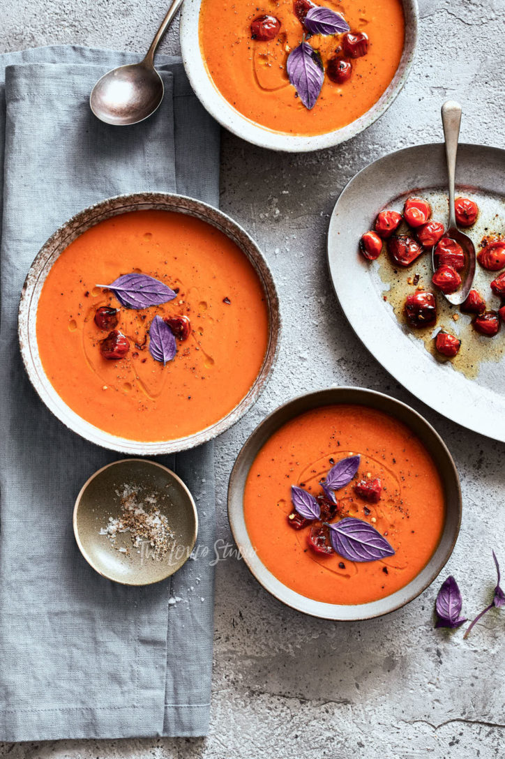 Three bowls of tomato soup with the green basil garnishes turned to purple.
