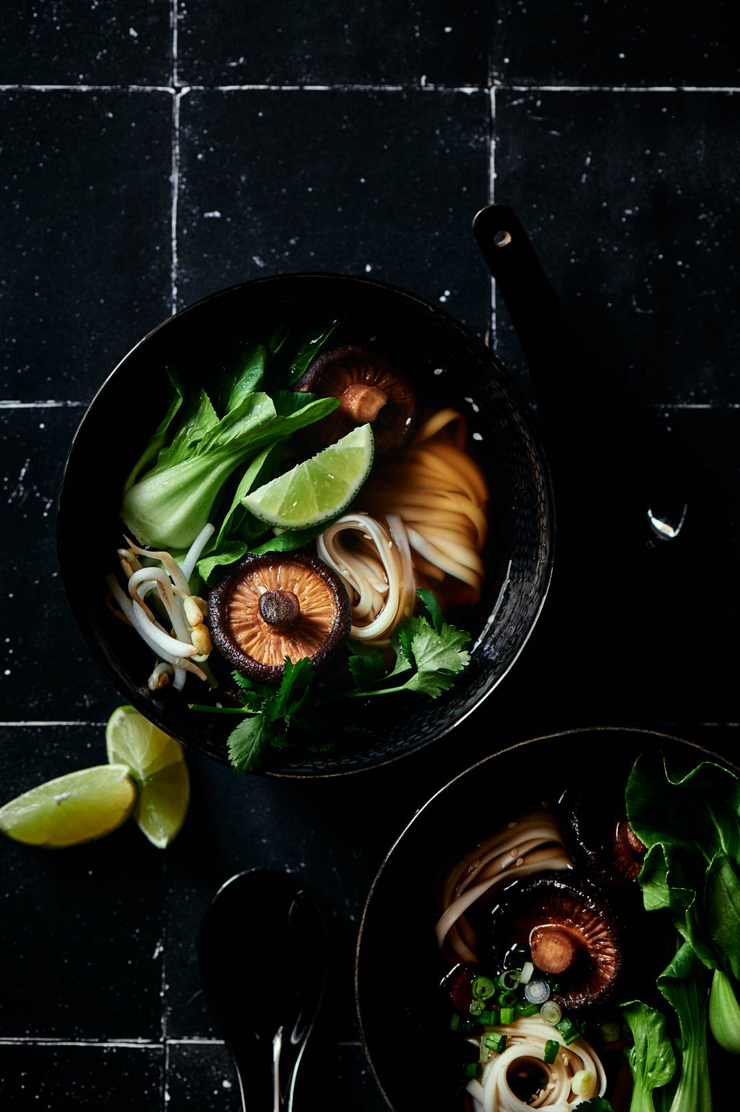 Dark background with noodles, slices of lime and mushrooms.