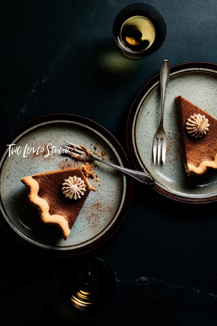 Dark background with blue speckled plates and slices of pumpkin pie.  