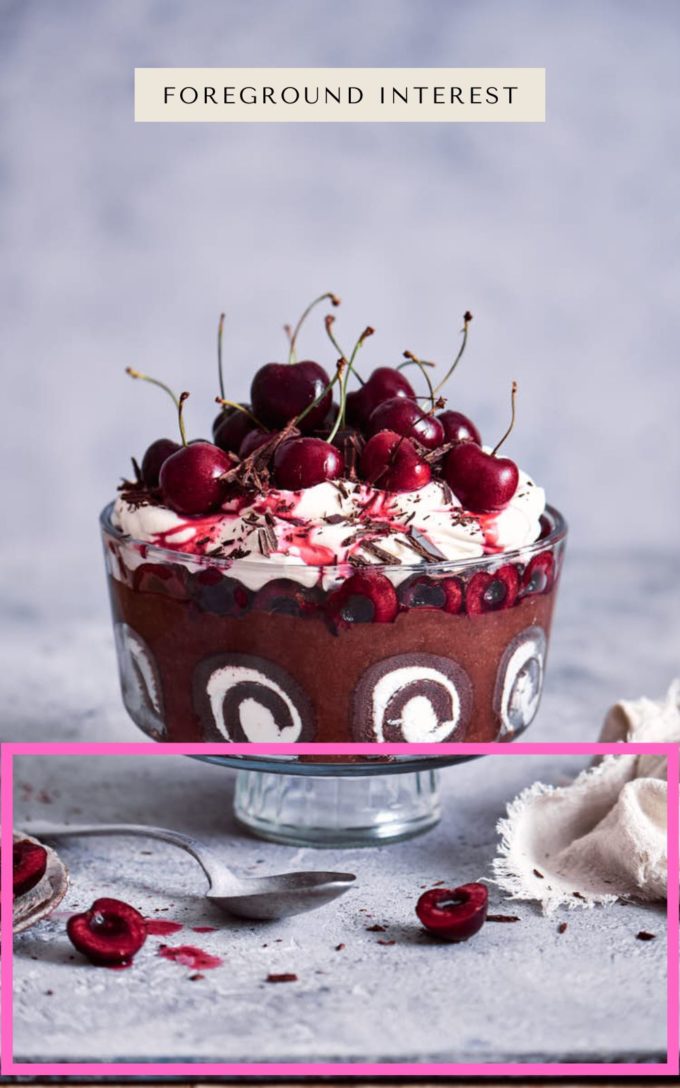 Foreground composition styling tips. Chocolate sponge cake in a class glass trifle dish. Topped with whipped cream and cherries.