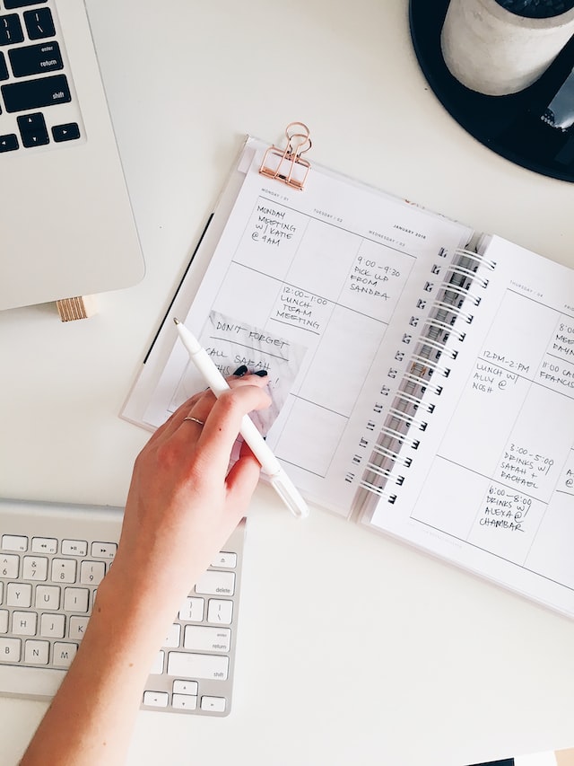 Open daily planner, lap top computer and keyboard planning out a daily agenda for pricing. 