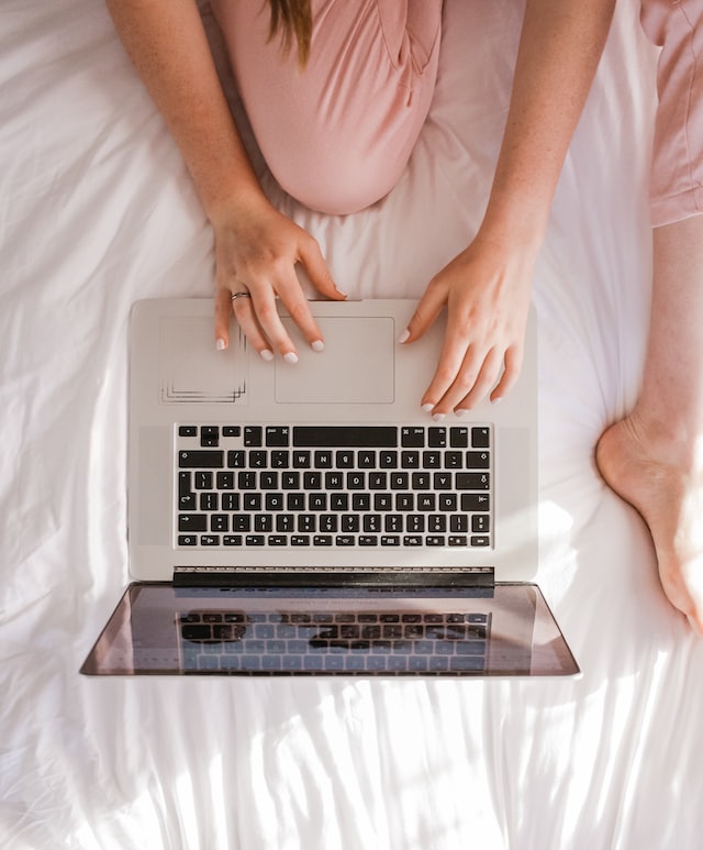 Women sitting on a bed with a laptop working on a food photography pricing sheet. 