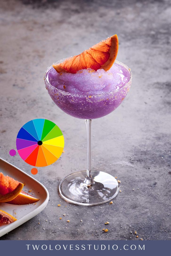 advanced color theories. Purple Frozen cocktail with orange wedge on top. 