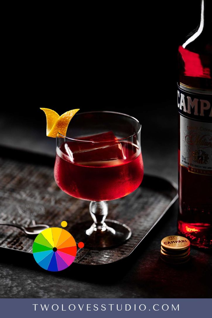 Example of a red and yellow Negroni cocktail, with a yellow orange twist. 
