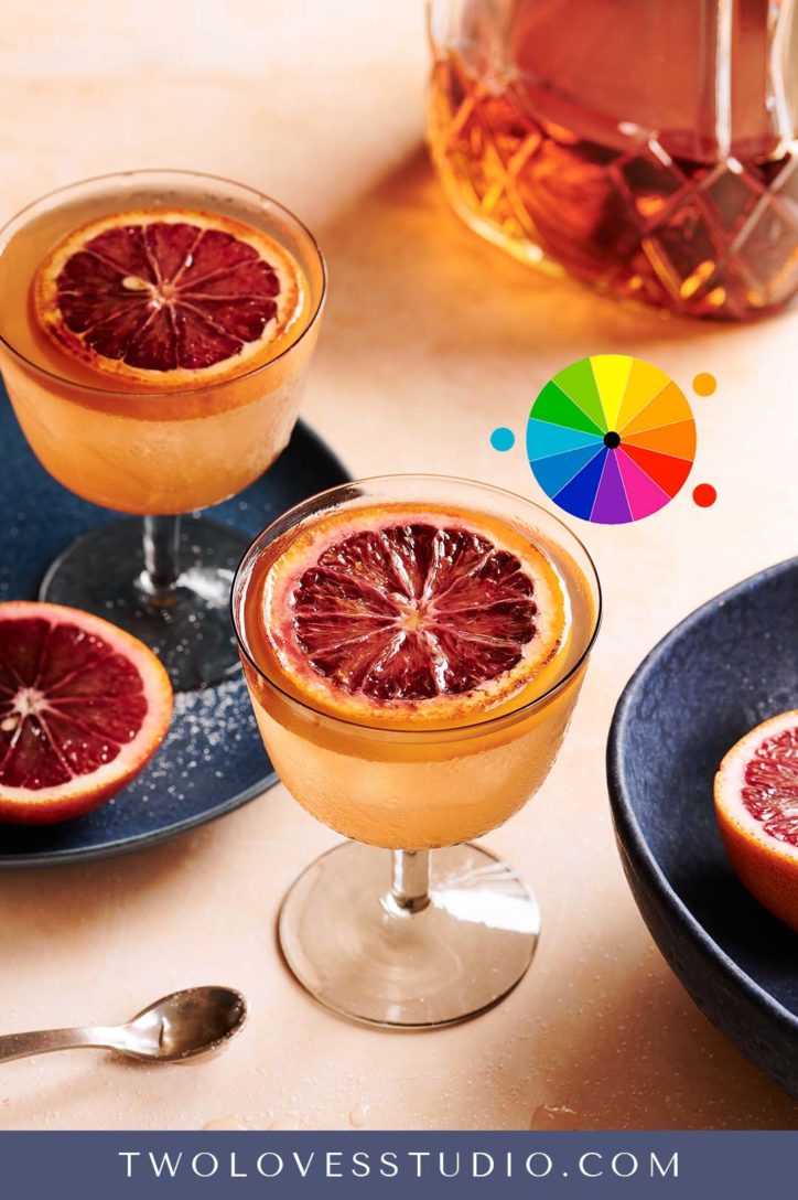 Whiskey sour shot with a bruleed orange on top, set on a sort background with blue bowls. 