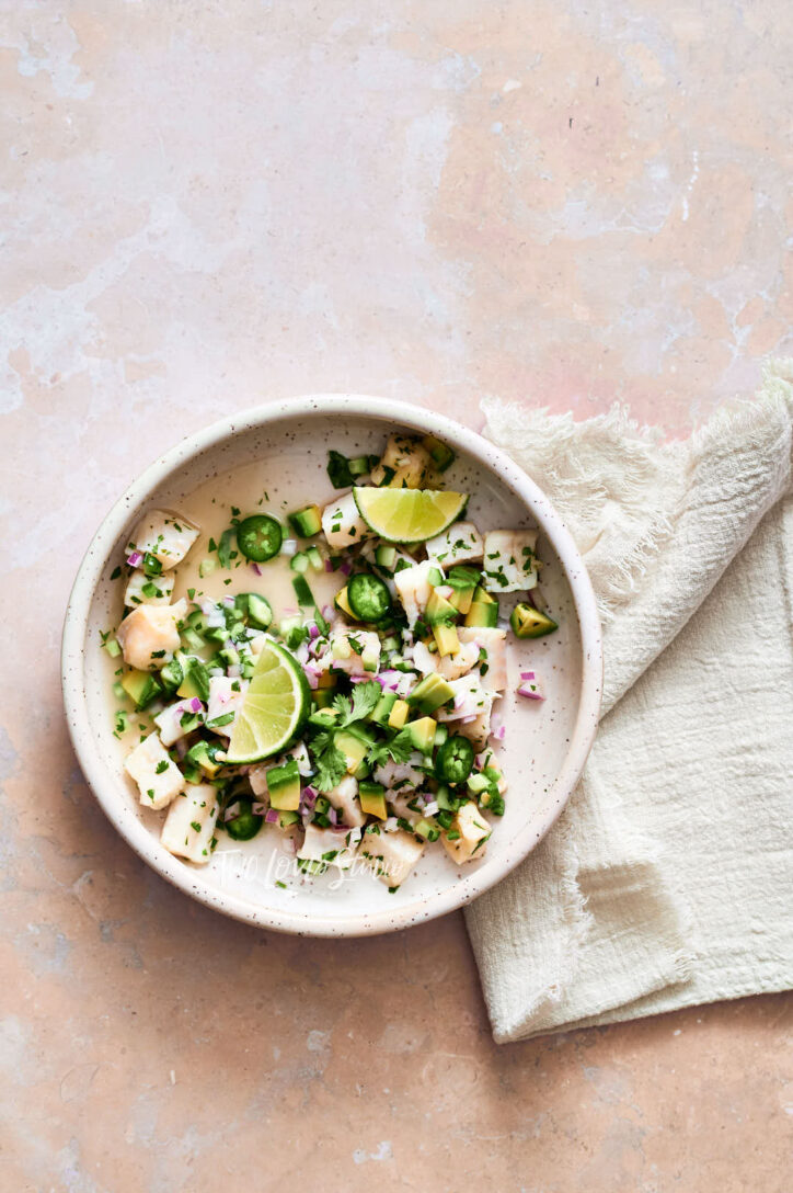 Pink background with a white linen napkin and fresh ceviche  