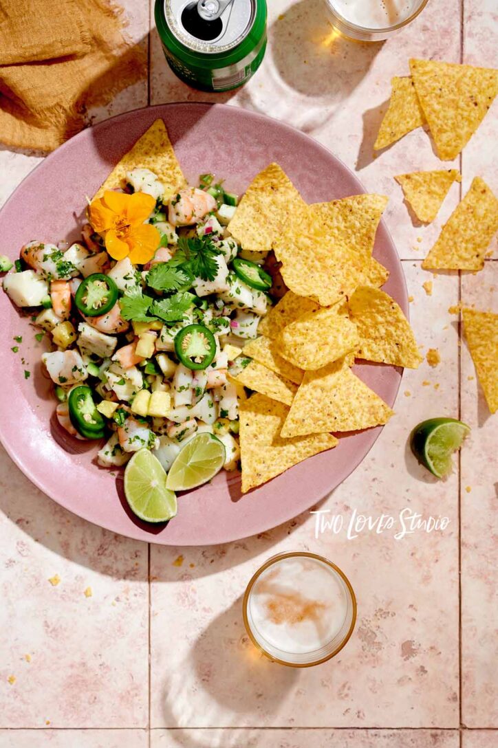 Ceviche on a pink plate with a beer and tortilla chips with hard light food photography