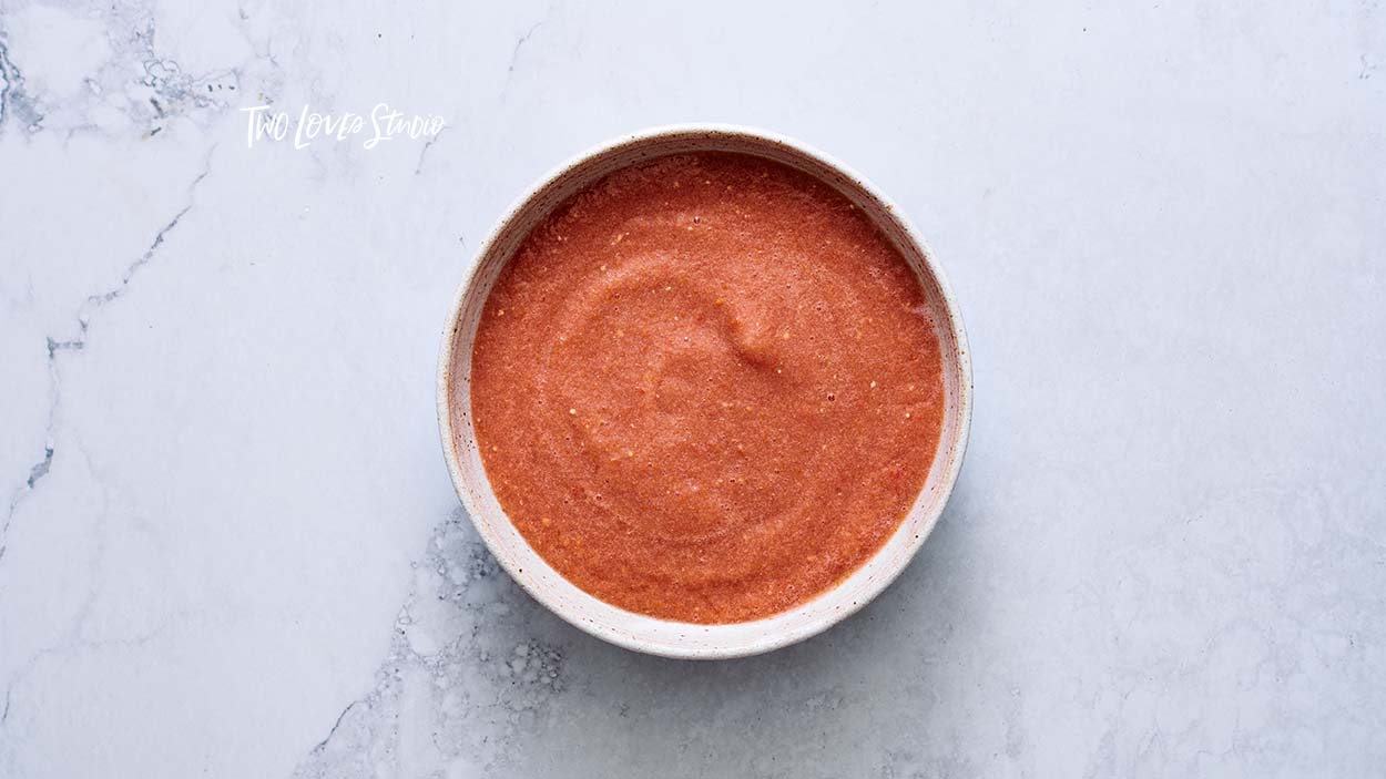 How-to-style soup, gazpacho. A bowl of red soup on a marble background.