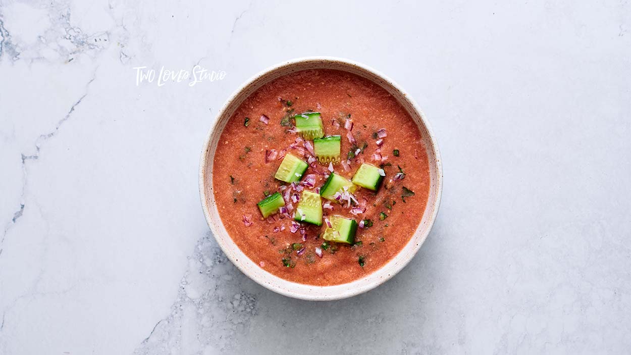 A bowl of gazpacho on a marble background.