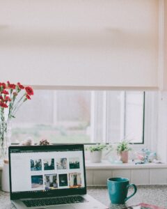 red flowers in vase beside laptop