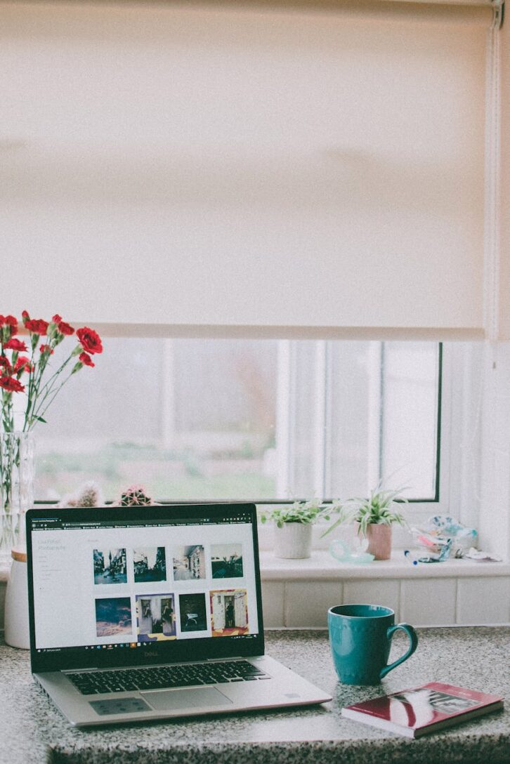 red flowers in vase beside laptop